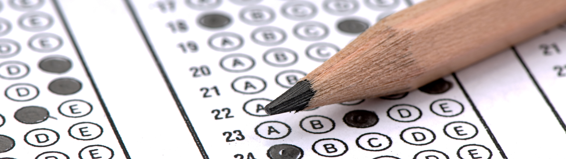 Close-up of a pencil on a multiple-choice exam sheet with answers filled in.